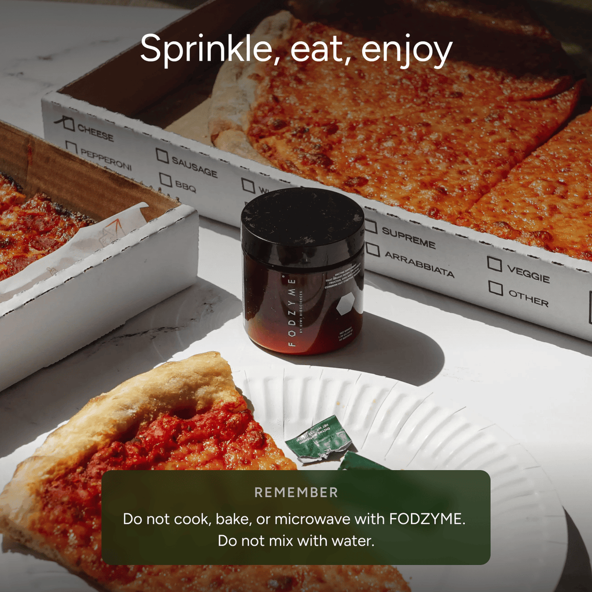 A jar of FODZYME food powder sits on a white plate with a slice of pizza and pizza boxes in the background, with text overlays reading 'Sprinkle, eat, enjoy' and 'REMEMBER Do not cook, bake, or microwave with FODZYME.'.